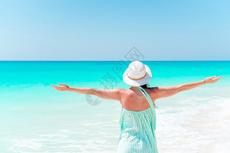 快乐的女子在海滩上放松后看着身帽子的女孩在海边人躺滩上享受暑假看着大海洋水休息图片