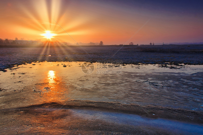 早晨太阳从冰冻的田地上升起太阳在2月时分风向末端笼罩着野外的冰层中反射季节蓝色的图片