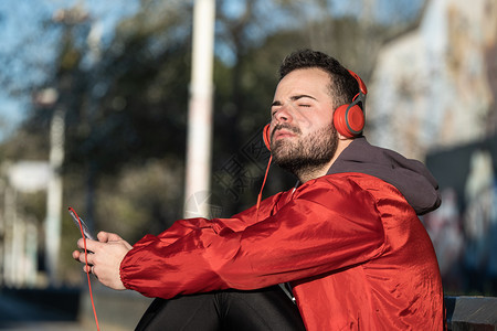松弛技术长椅参加运动的年轻人穿服用耳机听音乐图片