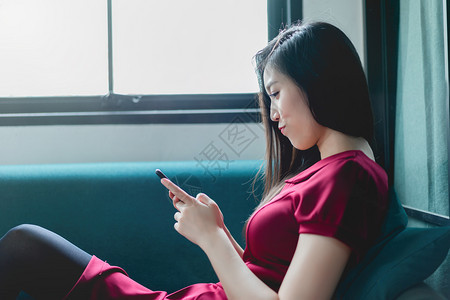 压力亚洲女孩在家中沙发上放松的肖像在家里客厅的智能手机上发短信人们美丽的图片