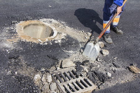 工作危险的街道维修路下水坑盖的公用事业工人图片
