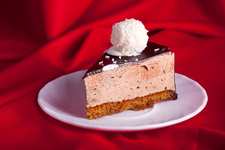 饮食棕色的奶油红丝绸背景的盘子上美味巧克力蛋糕浅色焦点图片