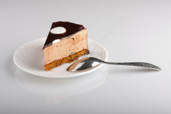 庆典白色的胖美味巧克力蛋糕餐盘上有勺子浅色焦点图片