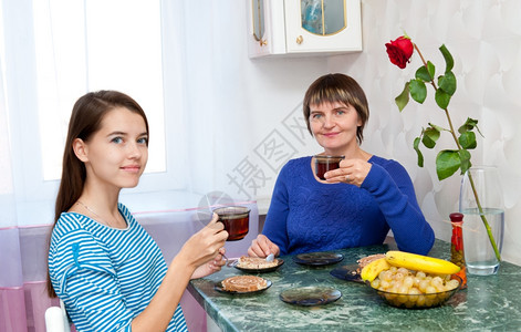 眼睛玫瑰在室内母亲和女儿一起喝茶图片