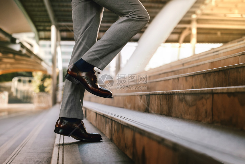 进入男人作为背景的创业者在现代城市阶梯上行走成功低层企业家中向前迈出进的事业概念阶段中的动力和具有挑战步进跳图片