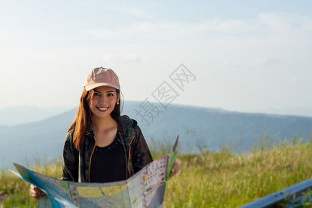 嘲笑冒险夏天背着明亮包的女亚洲在背景山上观光旅行者背后的视使用智能手机持有小工具的女用手图片