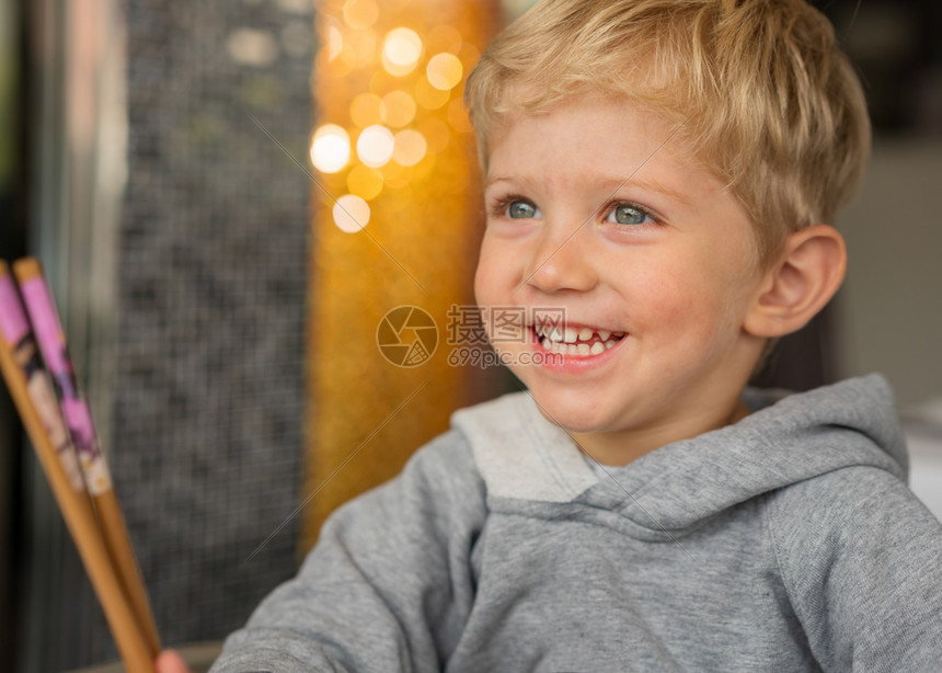 照片坐在高椅子上的婴儿男孩在餐馆玩筷子和笑的快乐背景有漂亮的bokoh横向相片孩子人图片