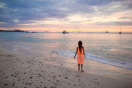 可爱快乐的小女孩日落时在海滩跳舞图片