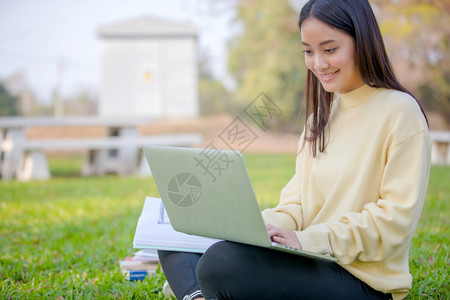 女大学生微笑着坐在草地上工作图片