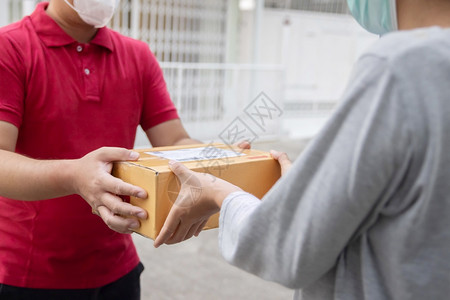 送货员穿戴面罩携带包裹给客户的邮差在线图片