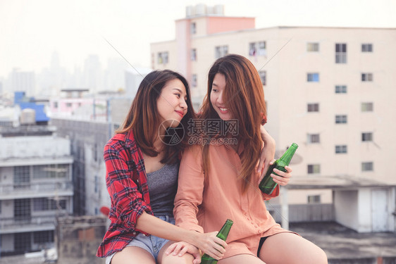 两个亚裔妇女饮酒在屋顶派对户外庆祝友谊女男双和变者夫妇女啤酒请享用图片