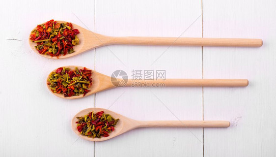 烹饪不同的三个木制勺子和白色桌上的香料胡椒子图片