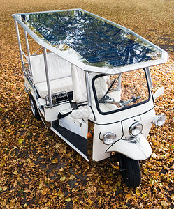 出租车聘请太阳能拖拉机停在公园的秋叶覆盖点上光伏图片
