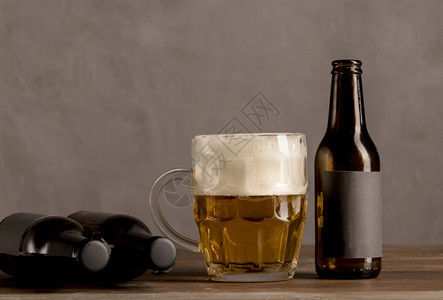 凉爽的低带有泡沫褐色瓶子的玻璃啤酒木制桌垂直的图片