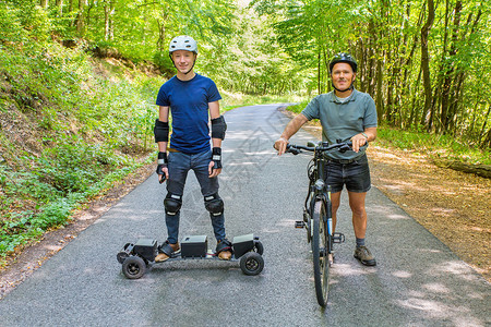 父亲和儿子站在山上骑着脚踏车在路上登山板滑积极的家庭图片