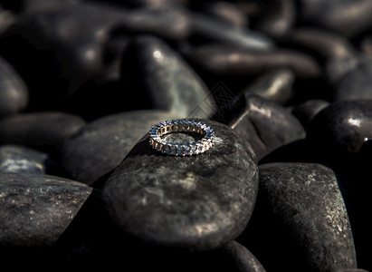 黑色的优雅手环装饰从体金属环多石块和模糊的金银女戒指其珠宝首饰印在石头背景上配饰图片