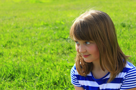 青草背景女孩的肖像画小时尚女孩在绿草背景上笑脸小时髦女孩在绿色草背景上孩子们傻笑春天图片
