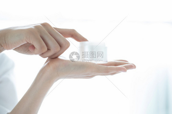 一位使用皮肤护理产品润湿剂或滑的美丽女亚洲人在手中照料她的干乳油奶肖像白色的新鲜图片