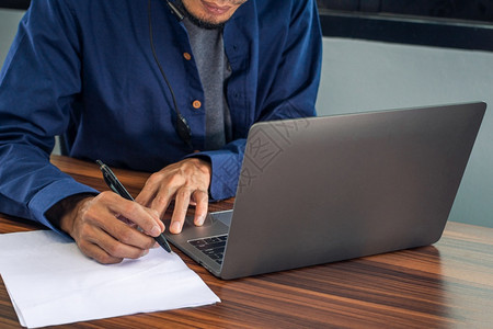 签约手以计算机笔记本在办公室工作商在家庭办公室作人在家等文件写的男子应用图片
