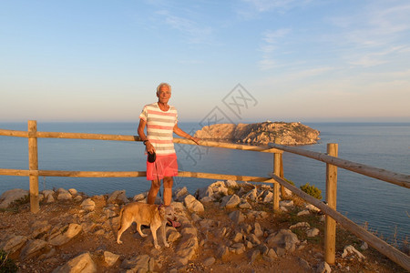 晚上假期灰色的在地平线夕阳下和莱斯梅德群岛一起带着狗走在风景前的人图片