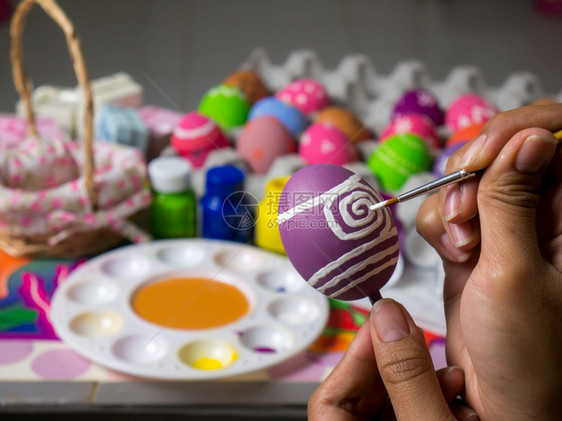 复活节妇女画在东方鸡蛋上的彩画在东方节的鸡蛋上美艺术作品以优美的方式与刷子一起绘制各种颜色的彩蛋装饰丰富多彩绿色图片