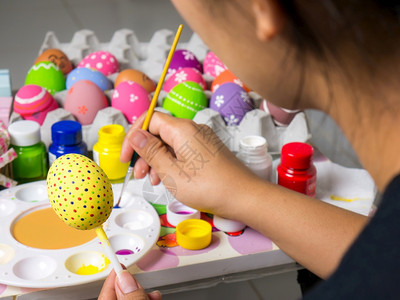 复活节妇女画在东方鸡蛋上的彩画在东方节的鸡蛋上美艺术作品以优美的方式与刷子一起绘制各种颜色的彩蛋假期四月美丽的图片