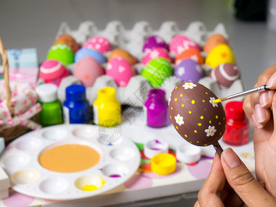 复活节妇女画在东方鸡蛋上的彩画在东方节的鸡蛋上美艺术作品以优美的方式与刷子一起绘制各种颜色的彩蛋紫粉节日图片