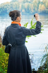 女孩公园拥有数码相机袋子和橙色围巾沿河拍照的优秀高级商业女等数字的图片