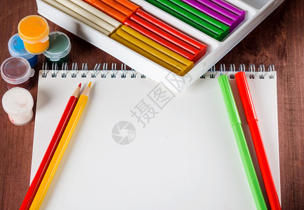 艺术的创造力木制背景上的纸铅笔和彩色油漆白纸板爱好图片