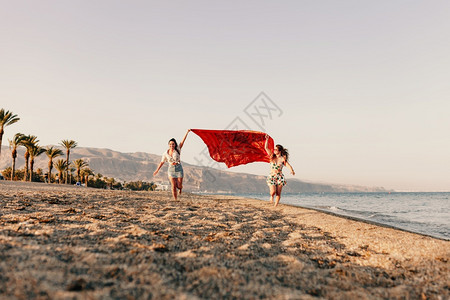 围巾跑步微笑有两个女人跑在波浪上围着巾在沙滩上放松快乐趣比基尼