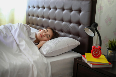 独自的松弛睡在白床上的亚洲美丽女士孩图片