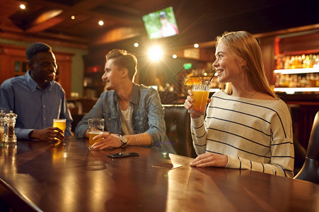 有三个朋友的酒精饮料在吧桌边玩得愉快的朋友一群人放松在酒吧夜生活友情庆祝动喝酒精饮料在吧玩得开心的朋友派对年轻谊图片