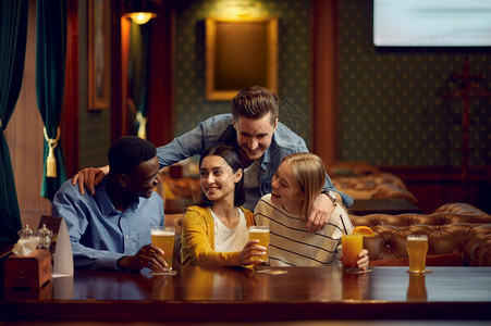 四个快乐的朋友在酒吧柜台喝一群人在吧放松夜间生活方式友谊动庆祝四个朋友在酒吧的柜台喝吐司玻璃微笑图片