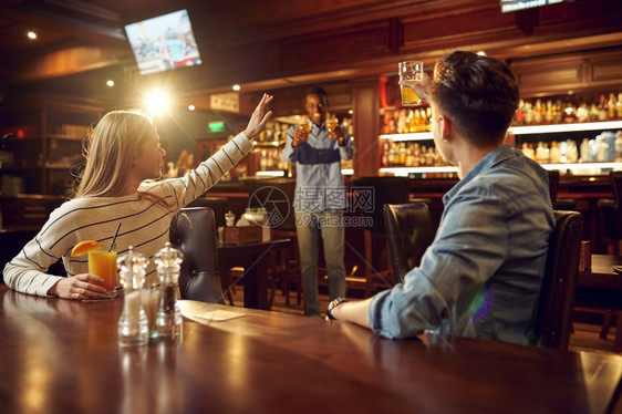 闲暇酒精团体朋友饮在吧桌边玩乐一群人放松在酒吧晚上的生活方式友谊庆祝活动朋友喝酒在吧过着开心的生活图片