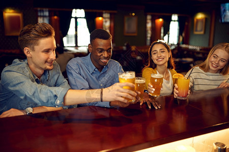 男人快乐的朋友在酒吧柜台喝啤一群人在吧放松夜间生活方式友谊动庆祝快乐的朋友在酒吧柜台喝啤俱乐部夜生活图片