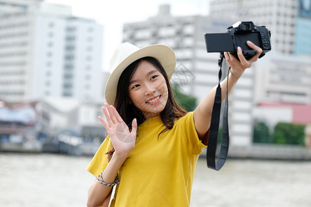 移动的时髦使用相机在城市自拍户外背景女自拍带有技术旅行和生活方式概念的户外人士以随意方式从事临时工作的年轻可爱亚洲女街道图片
