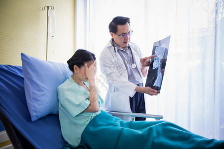 医生在向躺院床上的女病人解释脑X光检查结果图片