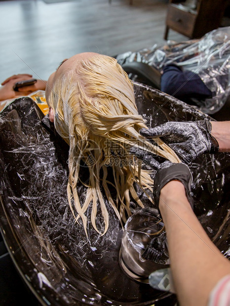 一种配件人们美发师为金女孩洗头为沙龙中的女专业染发美师为金女孩洗头图片
