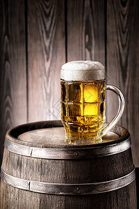 茶点生活材料面朝玻璃的轻啤酒在老旧木桶上加厚泡沫面朝玻璃的轻啤酒在玻璃上加厚泡沫图片