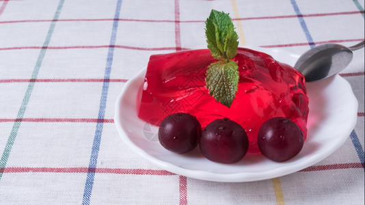 红色的草莓果冻盘子里有樱桃成熟的草莓果冻盘子里有成熟的樱桃闪亮露图片