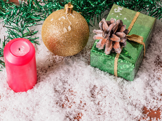传统的圣诞舞会红蜡烛和在雪中的礼物盒在树枝处的积雪中水果下的图片