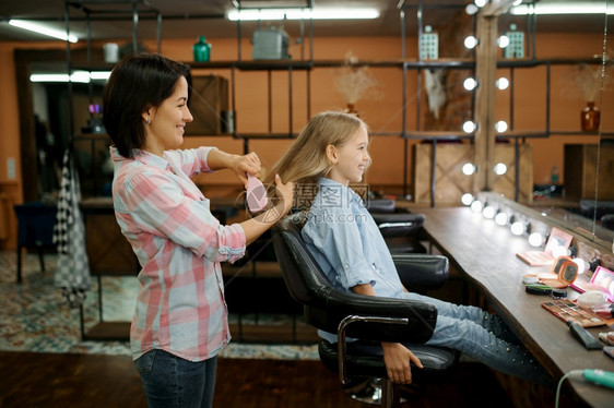 母亲和女儿在美容院做头发妈和小女孩一起打理发师快乐的童年迷人家庭母亲和女儿在沙龙做头发美丽母可爱的图片