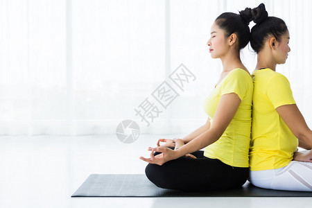 老师室内的两名亚洲年轻妇女在健身房练习瑜伽穿黄色礼服或与训练员和实习者一起表演冥想健康生活方式和健康概念摆姿势图片