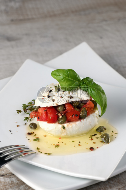 Mozzarella塞满西红柿的披风季节香料和油中的美食盘子服务图片