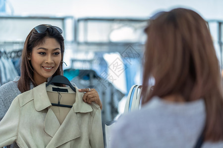 喜悦的亚洲妇女选择服装在商店里倒玻璃在省中心欢快的行动购买微笑随意的图片