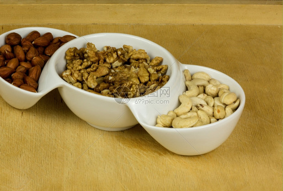 榛子三种新鲜的坚果印度杏仁麦加达米亚胡桃白碗中的栗子健康饮食横向一种吃图片
