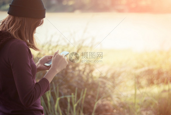 站立绿色夏天妇女站在公园里写智能手机文字的妇女图片