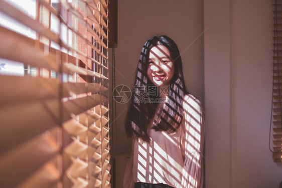 妇女在房间背景古年中站立在窗口上人们想家大厅图片