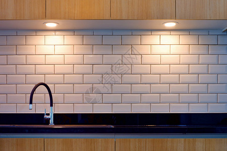 现代水龙头和黑棒下沉的色条纹前方白砖墙壁表面照明现代厨房风格的木制顶楼最小电灯泡光图片
