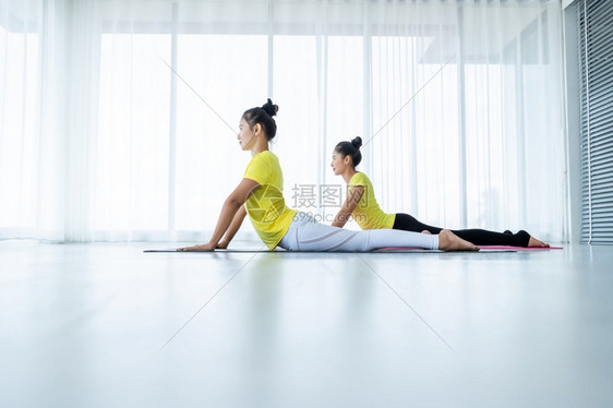 两名亚洲年轻妇女在健身房练习瑜伽穿黄色礼服或与训练员和实习者一起表演冥想健康生活方式和健康概念老师班级运动服图片